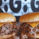 Two warm, sauce-drenched Beef Brisket Sandwich creations with melted cheese